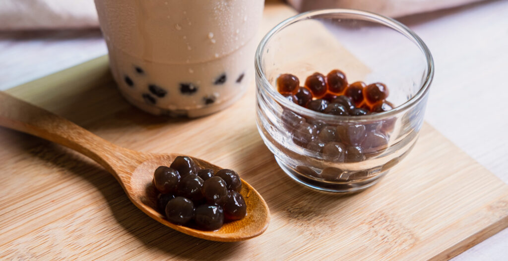 Bubble milk tea on wooden table with spoon displaying tapioca pearls 