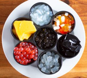 A top down view of a plate holding a variety of popular milk tea toppings and ingredients.